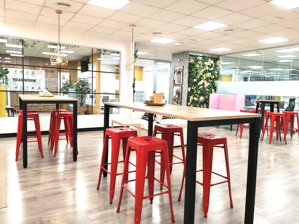 Zona colaborativa Teamwork con mesas altas y taburetes rojos