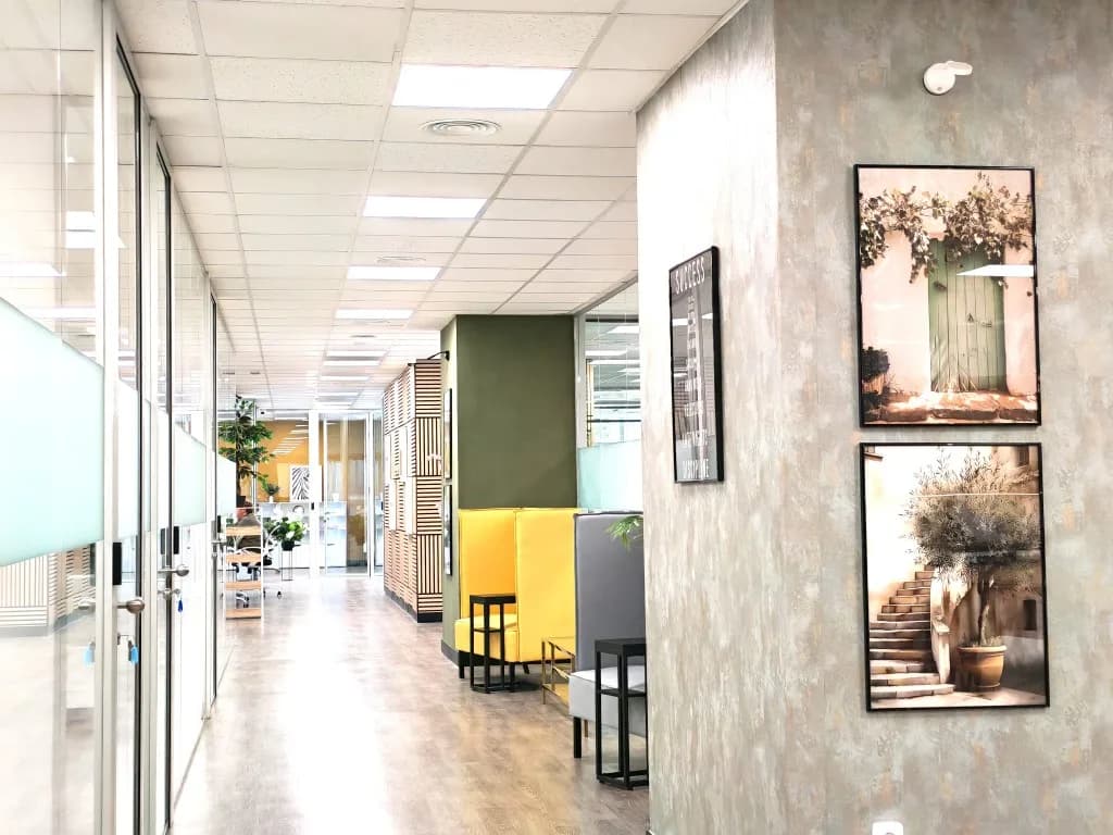 Pasillo de oficinas privadas con pared naranja y mamparas de cristal